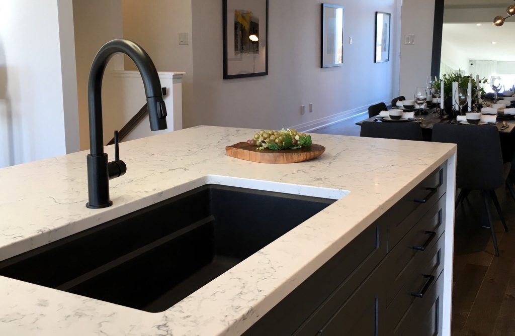 matte black kitchen faucet with a white marble waterfall countertop.