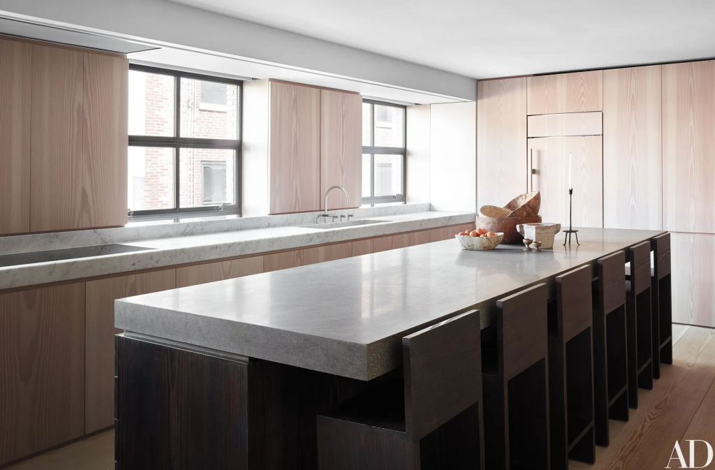 minimalist kitchen island with a cement counter and dark wood cabinets, stools with backs