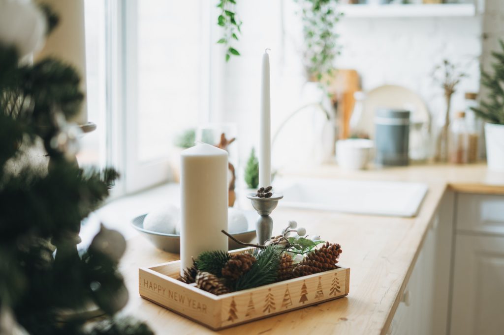 Christmas composition of white candles, pine branches and cones on the kitchen corner