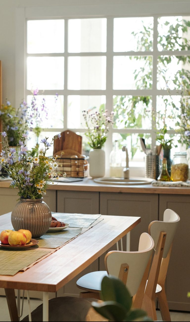 Cozy kitchen with wooden table in the center surrounded by sink with kitchenware