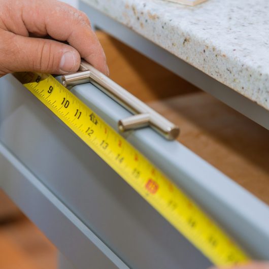 A carpenter is building a man measuring for a drawers in the kitchen cabinets