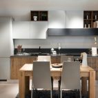 Compact modern kitchen or kitchenette with built in cabinets and appliances open plan to a small contemporary design chunky table and chairs