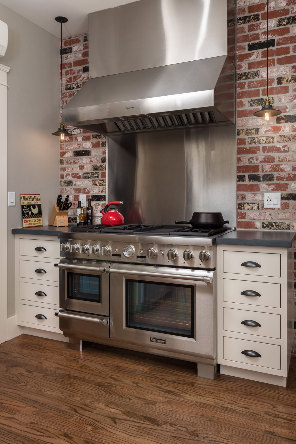 Large silver stove and oven combo with a brick wall