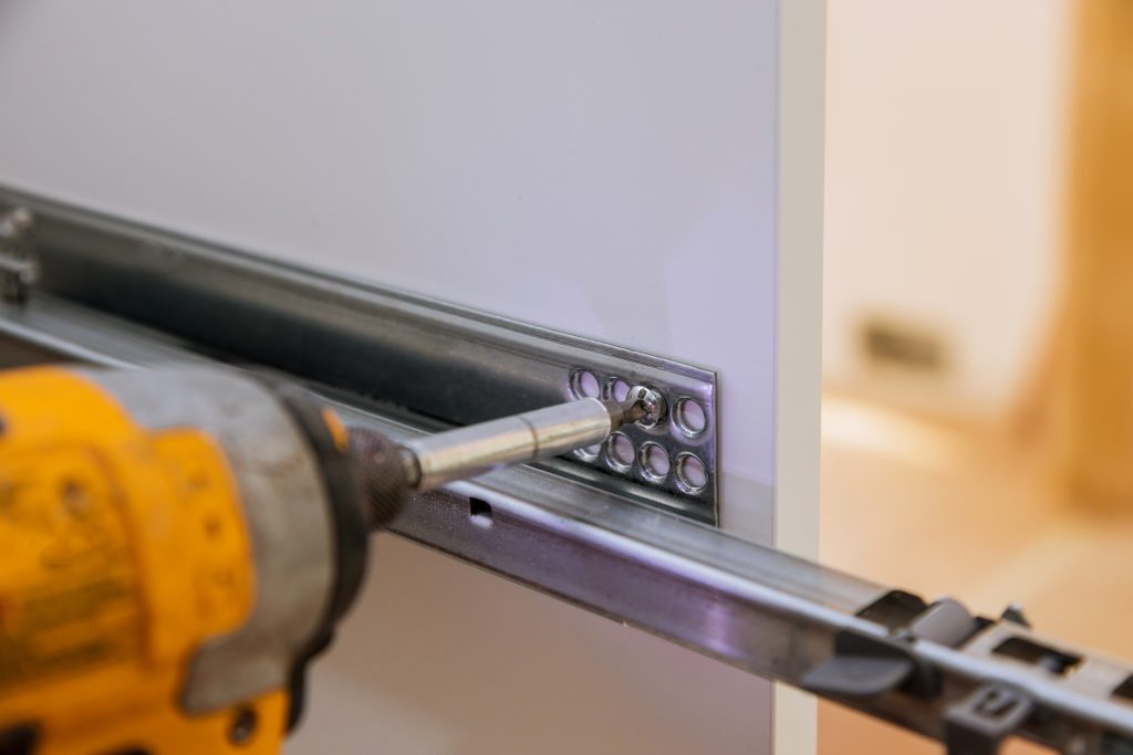 drawer slides being installed in a set of cabinets