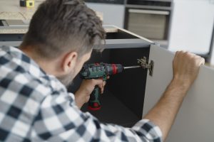 Man installing hinges in kitchen furniture