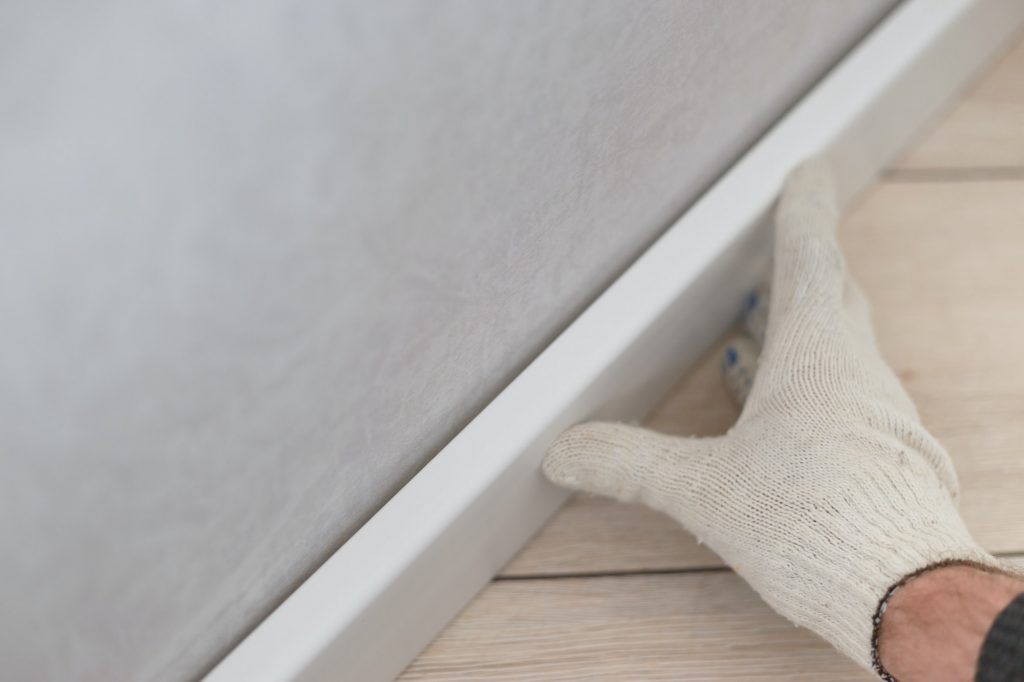 Man putting new skirting board on wall in house